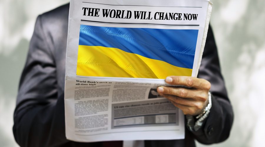 signore non identificato ha un giornale in mano che riporta la bandiera dell'Ucraina e la scritta in alto the world will change now