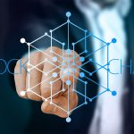 scritta blockchain con dito che indica forma virtuale che si apre