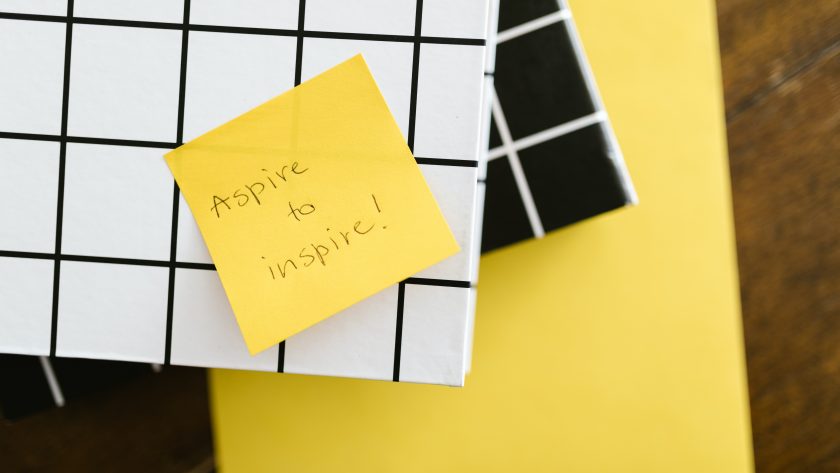 post-it su un quaderno con scritto su ''aspire to inspire''